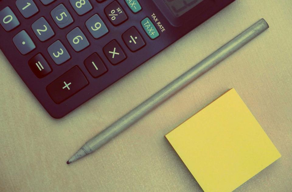 Calculadora y documentos financieros para revisar la factura eléctrica de una empresa